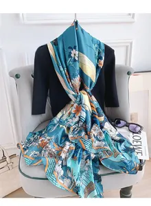 Detail view of the floral silk satin scarf featuring cyan blue tones and orange flower prints