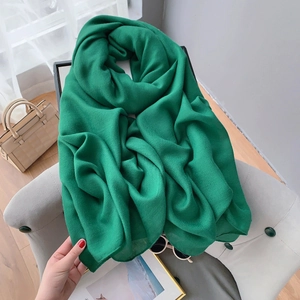 Detailed texture of dark green linen scarf draped on a sofa in a lifestyle setting