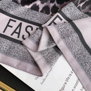 Macro detail of silk scarf showing leopard print and lettering with high-end texture