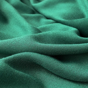 Macro view of dark green linen fabric showing fine grain texture and soft draping effect