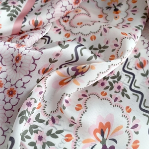 Detailed view of floral silk scarf showing satin texture and colorful vine patterns