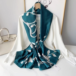 Peacock green floral silk scarf with beige flower pattern draped on white shirt