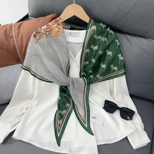 Élégant foulard en soie à motif zèbre vert associé à un chemisier blanc sur cintre