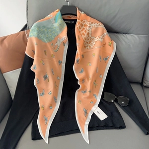 Foulard en soie rose orangé avec imprimé girafe et papillons sur un haut noir en V