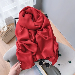 Detailed texture of a red long linen scarf draped on a chair for summer styling