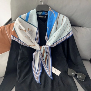 Close-up of a blue and orange horse print silk scarf tied on a stylish black V-neck shirt