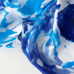 Detailed macro shot of abstract blue and white ink wash patterns on silky scarf fabric