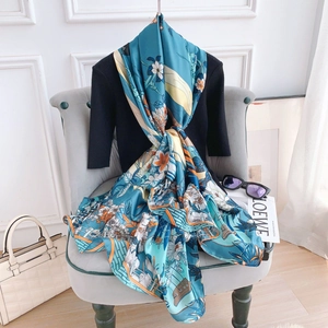 Detail of tropical floral print silk scarf with peacock blue base and orange accents