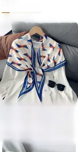 Détail d'un foulard en soie fin aux motifs géométriques orange et bleu sur chemise