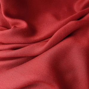 Detailed macro view of the premium red linen fabric texture with elegant drapes and soft sheen