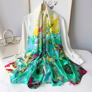 Detail of a silky long scarf with colorful floral prints draped over a white blouse