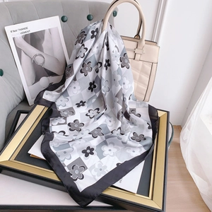 Dettaglio di un foulard quadrato in finta seta con motivo floreale e scacchi su una borsa