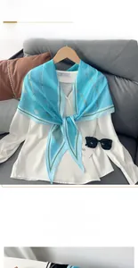 Détail d'un foulard en soie géométrique bleu et blanc sur un chemisier blanc