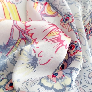 Close-up of silk scarf fabric showing elegant floral print and smooth glossy texture