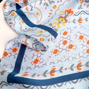 Macro shot of light blue floral silk scarf with twill texture and bohemian pattern