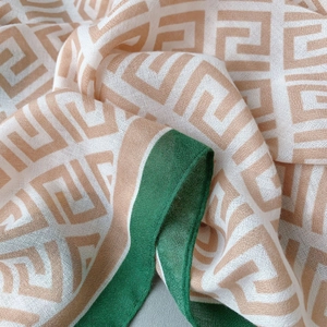 Detail shot of breathable cotton linen scarf with green stitching and geometric patterns