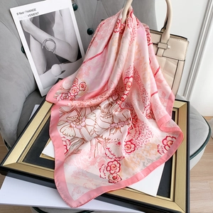 Close-up of pink floral silk scarf draped on a frame with artistic magazine background