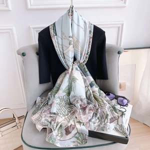 Detailed view of elegant floral pattern on light green silk scarf draped on a chair