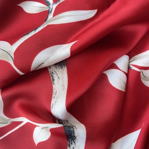 Macro detail of red floral silk scarf fabric showing smooth texture and elegant drape