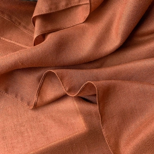 Macro detail of breathable caramel linen scarf fabric showing weave texture and hem stitch
