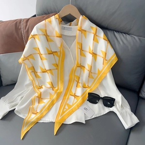 Détail d'un foulard en soie jaune vif à motifs géométriques stylisé sur une chemise