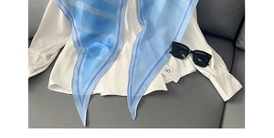 Vue détaillée d'un foulard en soie rayé bleu et blanc avec une chemise et des lunettes