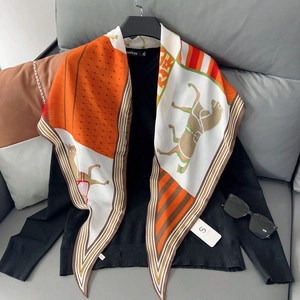 Close-up of geometric orange horse print silk scarf styled with a black V-neck shirt