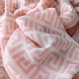 Detailed macro view of pink and white cotton linen scarf with geometric maze patterns
