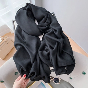 Detail shot of soft black linen cotton scarf draped on a modern grey chair