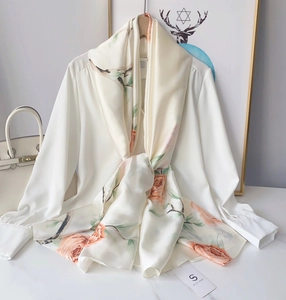 Detailed view of beige rose print silk scarf paired with a white long sleeve shirt