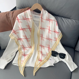 Détail d'un foulard en soie à motifs géométriques sur une chemise blanche en mousseline