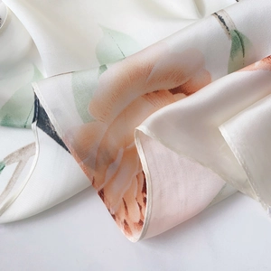 Detailed macro view of beige floral silk scarf with elegant rolled hem and pearl luster