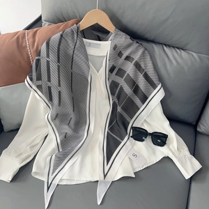 Détail d'une chemise blanche avec un foulard en soie à rayures géométriques noires et blanches