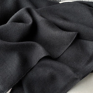 Close-up of black linen cotton scarf fabric showing natural wrinkles and fine texture