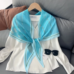 Détail d'un foulard en soie rayé et d'un chemisier blanc avec des lunettes de soleil