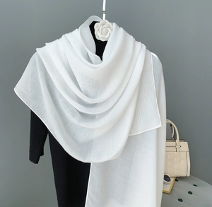 Detail view of lightweight white linen scarf texture with elegant camellia hanger display