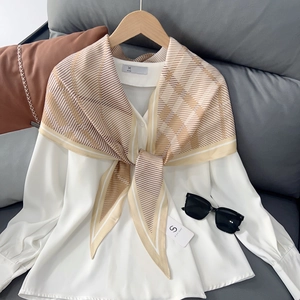 Élégant foulard en soie rayé d'été noué sur une chemise blanche pour protection solaire