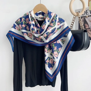 Élégant foulard en soie avec bordure marine et motifs floraux roses sur un cintre