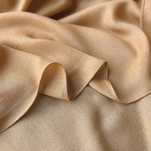 Macro shot of shimmering camel linen scarf fabric with delicate stitched edge detail