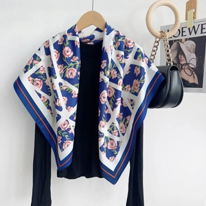 Détail d'un foulard carré à motif floral bleu marine et blanc sur un cintre en bois