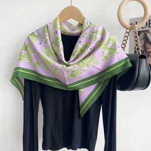 Écharpe en soie fleurie vert et mauve drapée sur un haut noir avec des accessoires