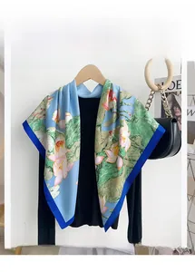 Detailed shot of large floral square scarf with lotus print on blue green silk texture
