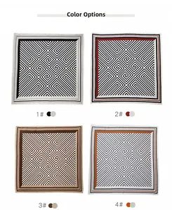 Détail d'un foulard carré en soie montrant des motifs géométriques en noir, rouge et brun