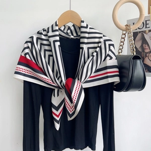 Détail d'un foulard en soie à motif géométrique avec haut noir et sac à bandoulière