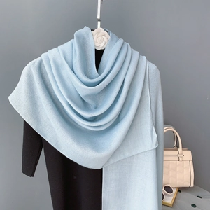 Detail of light blue linen scarf showing soft drape texture and layered fabric folds