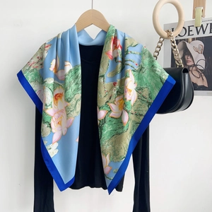 Detail of blue silk scarf with pink lotus print and dark contrast border on black sweater