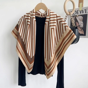 Détail d'un foulard carré effet soie aux rayures géométriques marron et blanc sur un haut