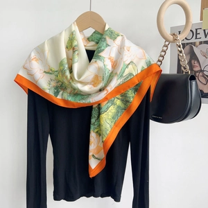 Floral print faux silk square scarf with orange borders on a minimalist wooden hanger