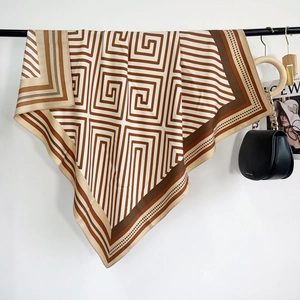 Détail d'un grand foulard carré en soie avec motif grec marron et texture élégante et lisse