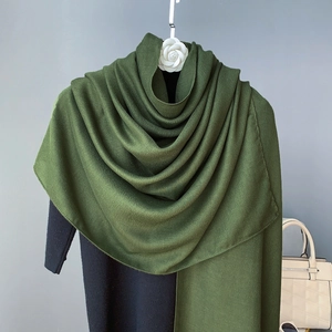 Detail of olive green knitted scarf draped on a quilted bag and decorative hanger